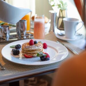 Pouring syrup over fresh pancakes during a luxurious slow morning at sea.