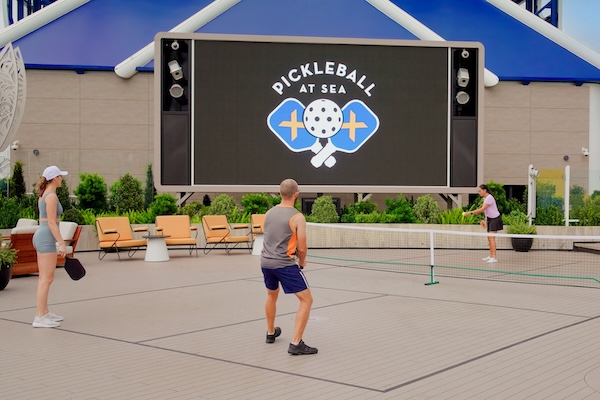 Active couples enjoying a game of pickleball at sea during a marriage retreat downtime.