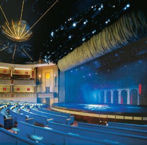 Spacious theatre aboard for the Christian marriage cruise, featuring rows of blue seating.